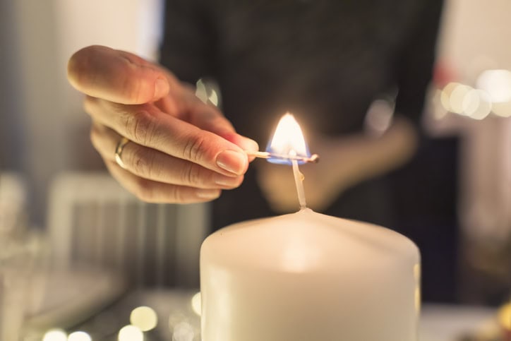 Person tenner lys på en festlig anledning med stearinlys og dekorasjoner.
