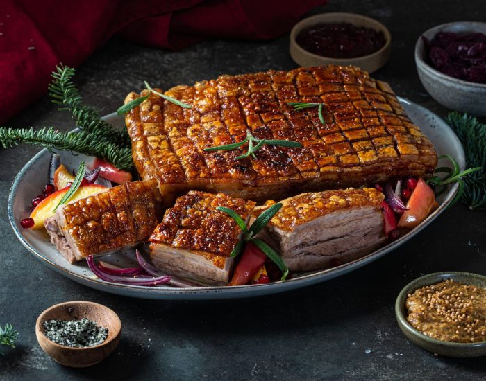 Perfekt stekt svinekam med sprø svor, servert med tilbehør og juleinspirert pynt.