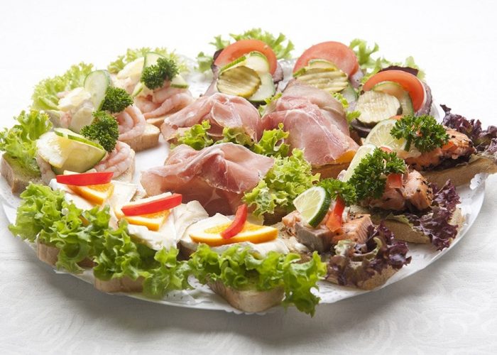 Utvalg av fersk lunsjmat med kjøtt, ost og grønnsaker på fat.